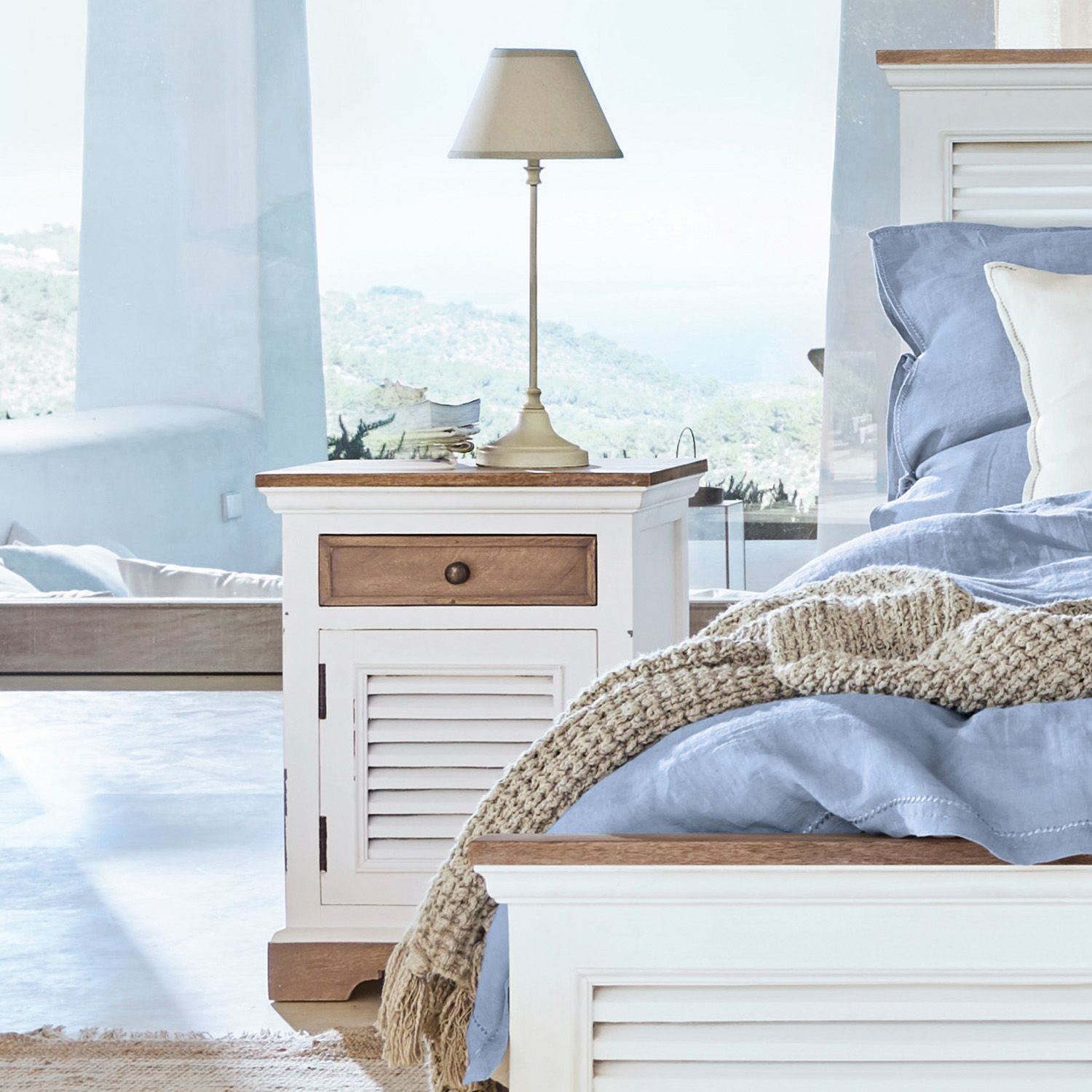 Weißer Holz-Nachttisch mit Schublade und Lampe im Schlafzimmer mit blauer Bettwäsche