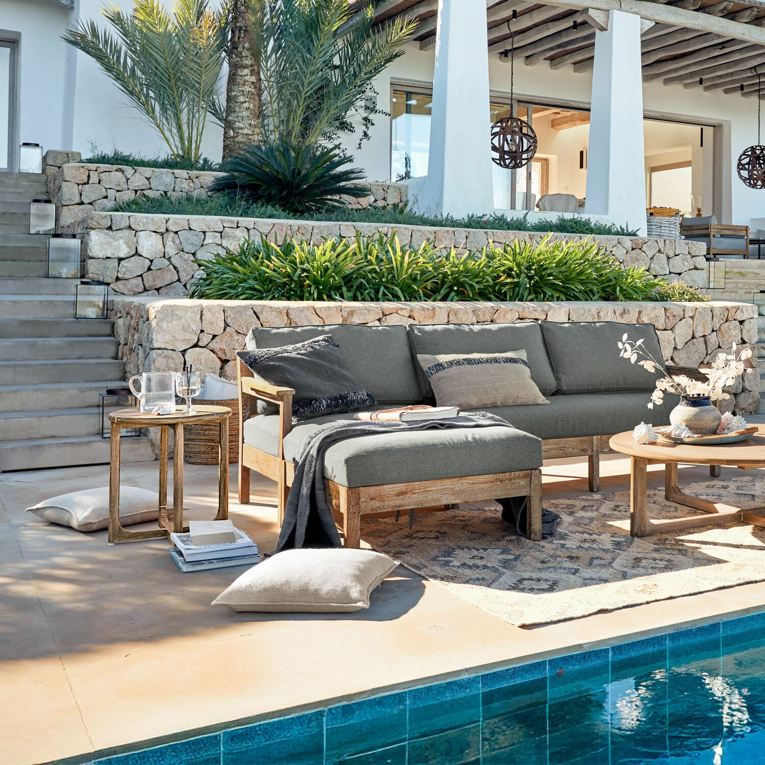 Graues Ecksofa mit Holzrahmen auf Terrasse am Pool mit Kissen und Beistelltischen