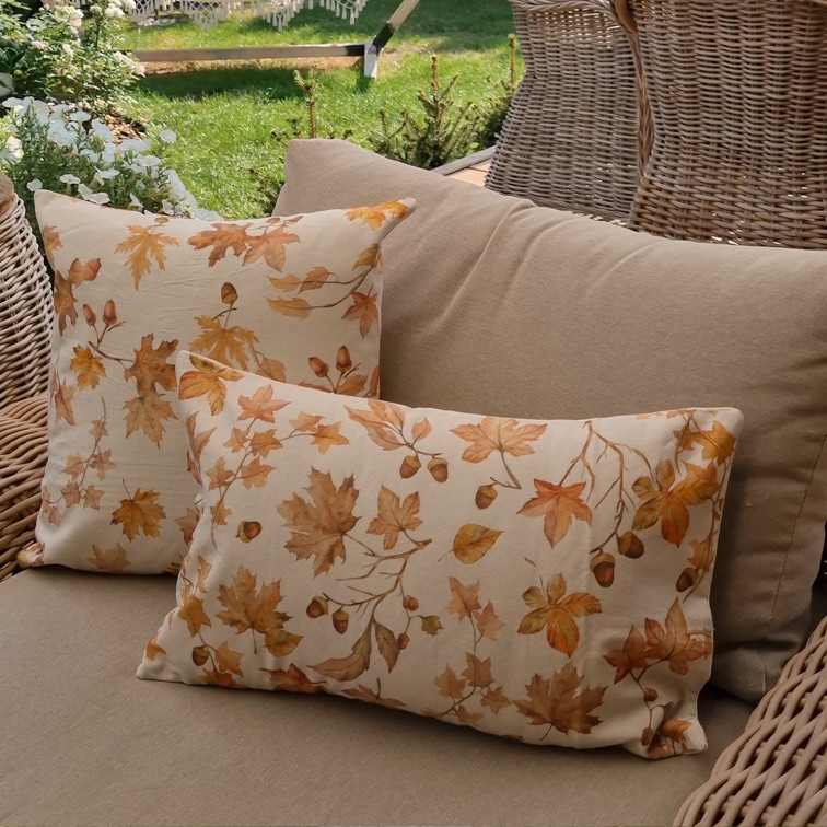 Dekorative Baumwollkissen in Beige mit herbstlichem Blatt- und Eichelmuster auf Gartenlounge aus Rattan