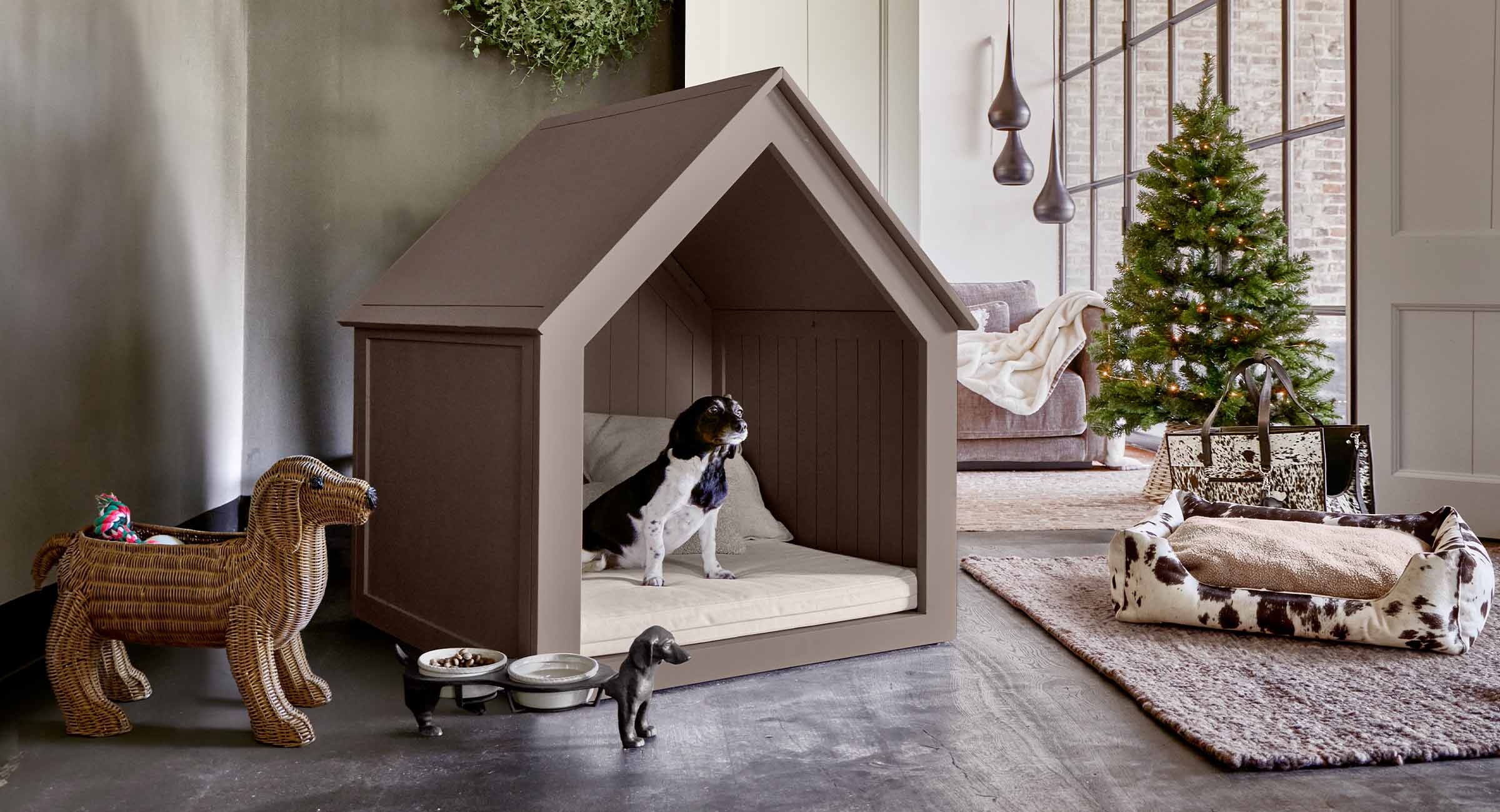 Braunes Hundehäuschen aus Holz mit cremefarbenem Kissen in modernem Wohnzimmer mit Weihnachtsbaum und Spielzeug