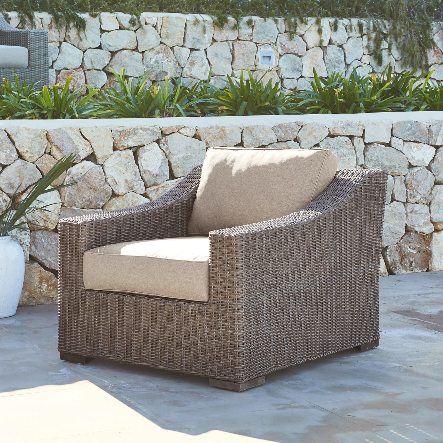Gartenfauteuil aus braunem Rattan mit beigen Kissen, ideal für Terrasse und Garten