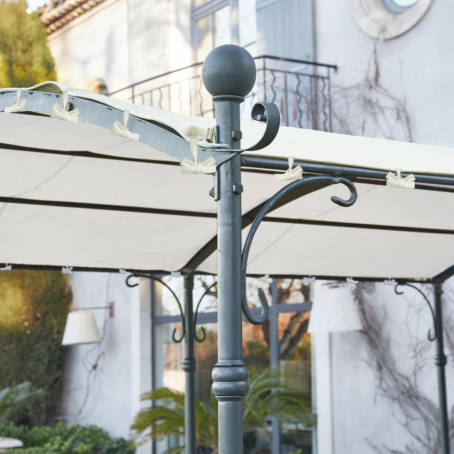 Metallgestell einer Pergola mit cremefarbenem Stoffdach im Gartenbereich