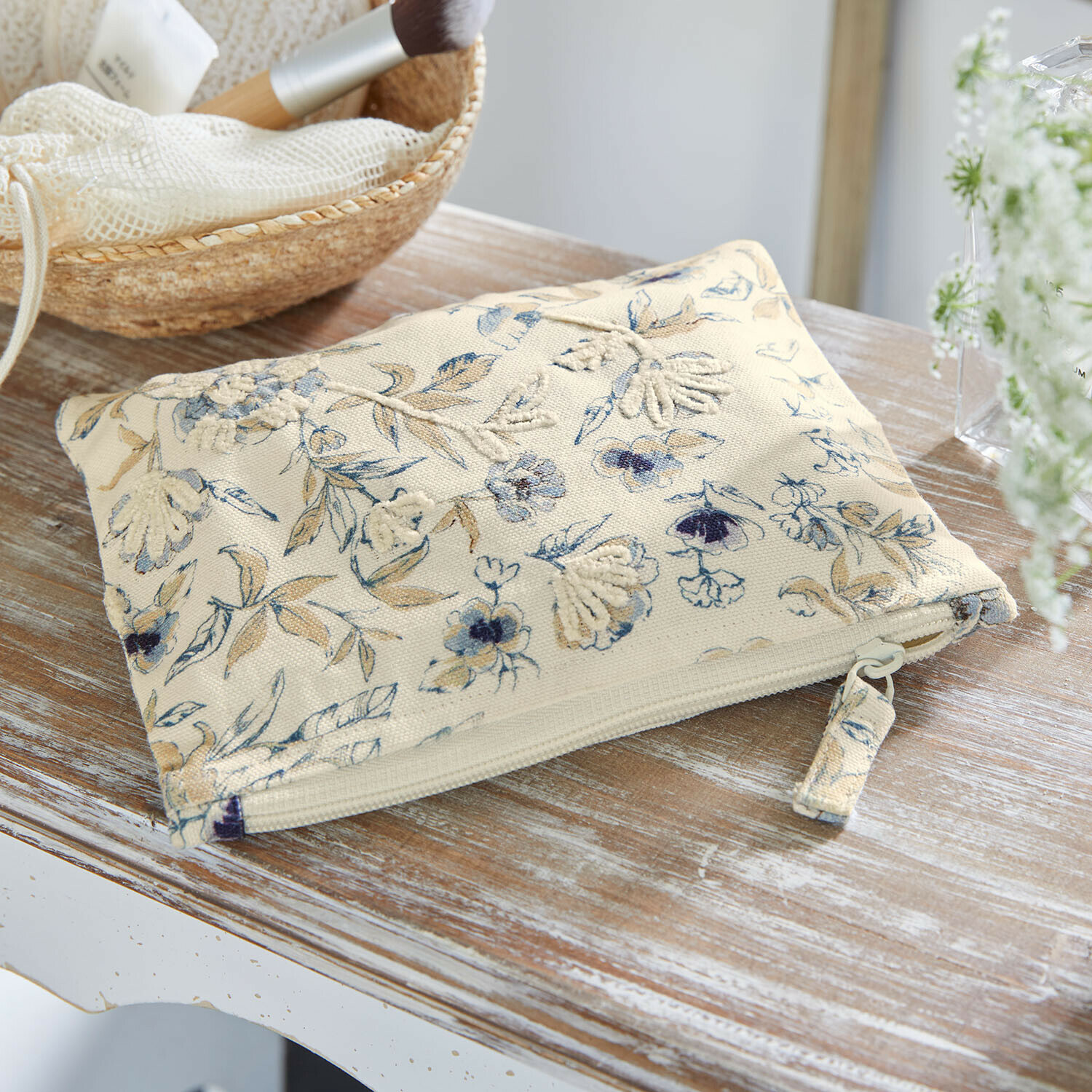 Beige Kosmetiktasche aus Baumwolle mit blau-braunem Blumenmuster und Reißverschluss auf Holztisch