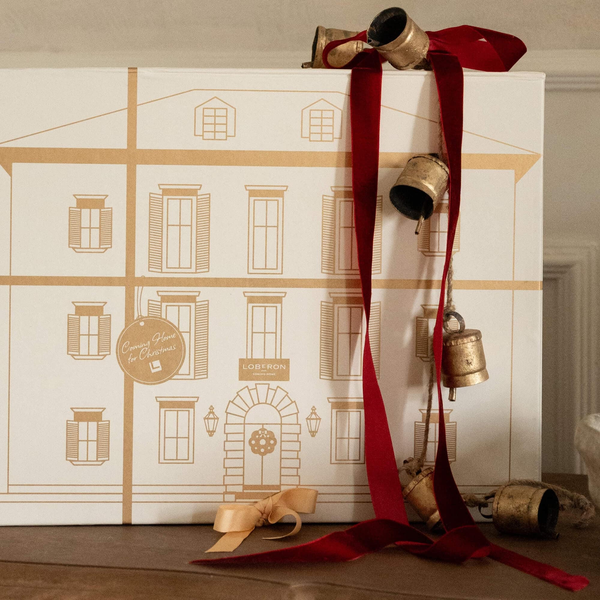 Weihnachtliche Dekoration mit roten Bändern und goldenen Glocken vor weißem Hintergrund mit Hauszeichnung