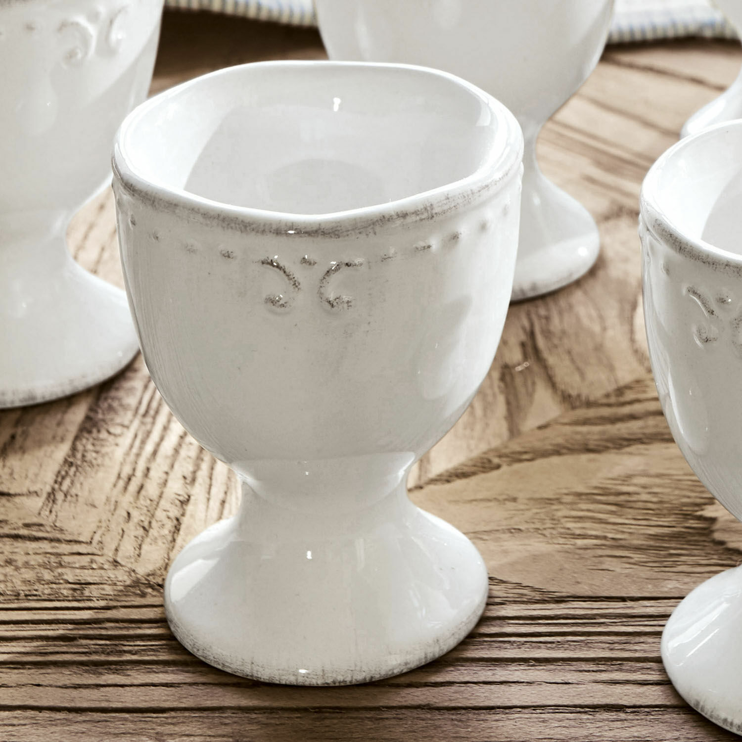 Weißer Keramik-Eierbecher mit feiner Verzierung auf Holztisch, Küchenzubehör