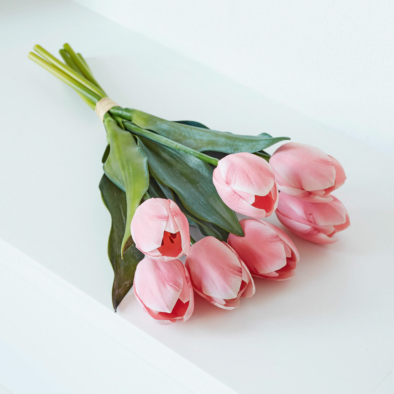Strauß rosa Tulpen mit grünen Blättern auf weißem Hintergrund, Frühlingsdekoration