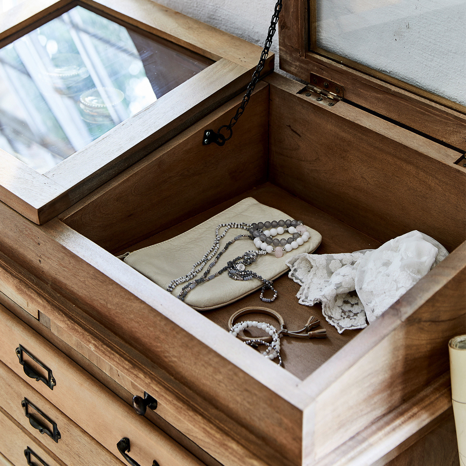 Holzschatulle mit Glasdeckel und Schmuck auf cremefarbenem Kissen, natürliche Holzfarbe