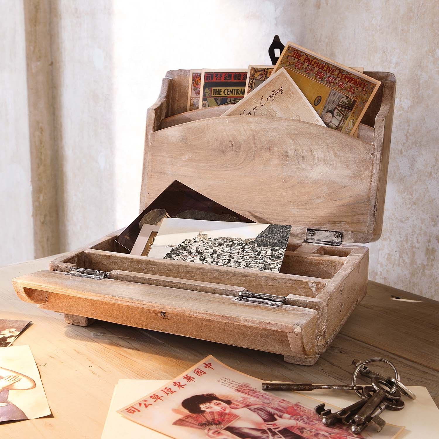 Holzbriefkasten in Naturfarbe mit Vintage-Postkarten und alten Metallschlüsseln auf Holztisch