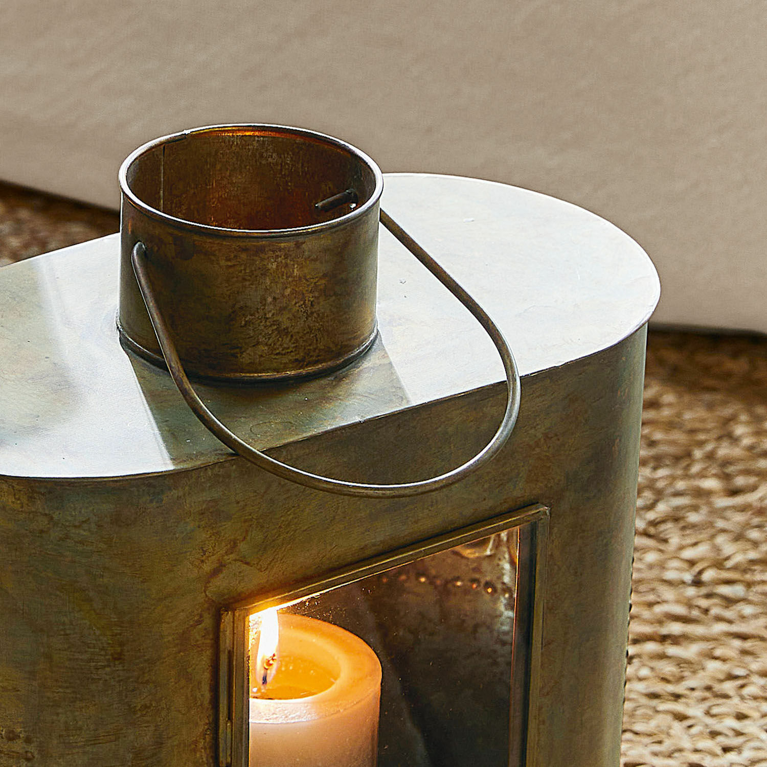 Metalllaterne mit Griff und brennender weißer Kerze als Wohnaccessoire