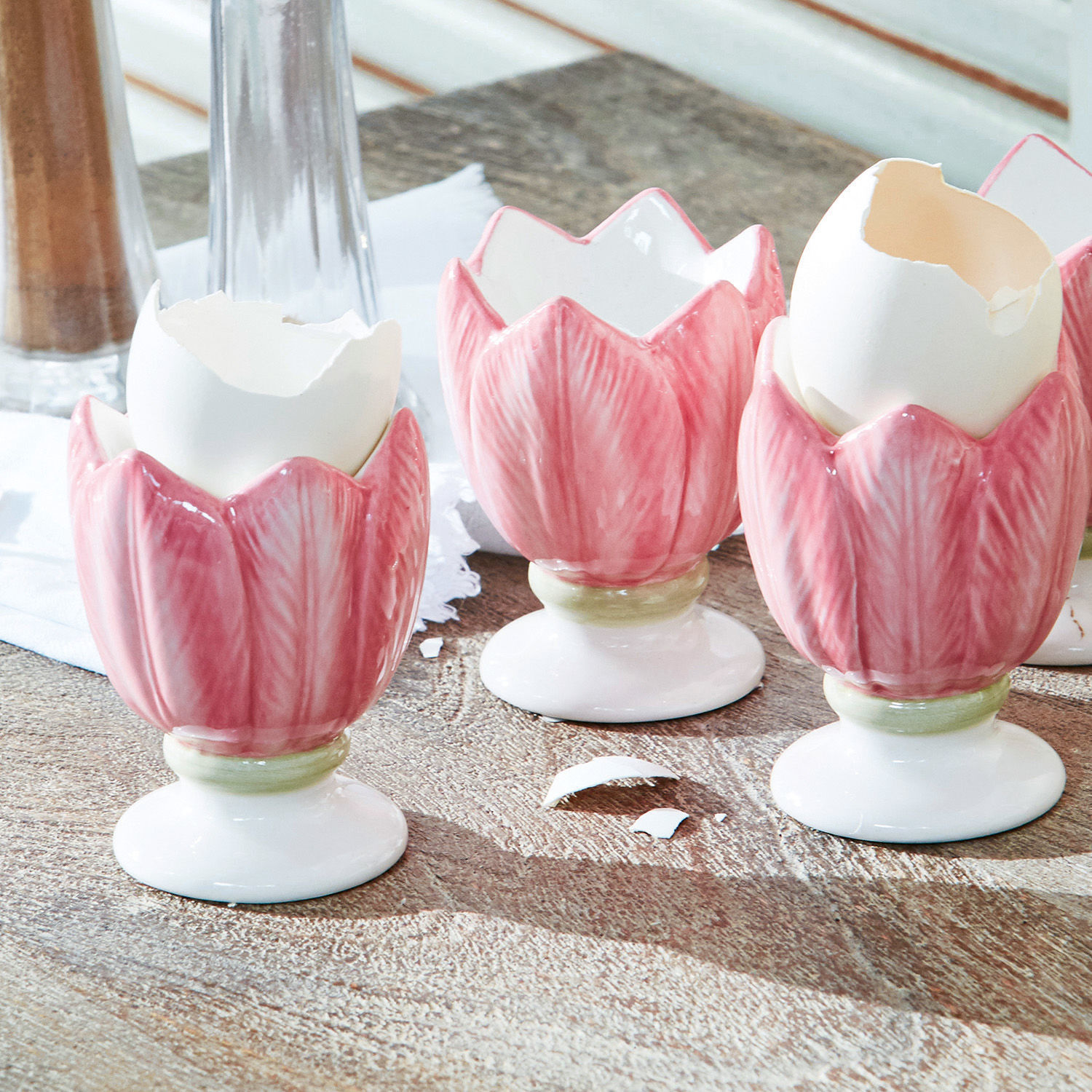 Keramische rosa Eierbecher in Tulpenform auf Holztisch als Tischdekoration