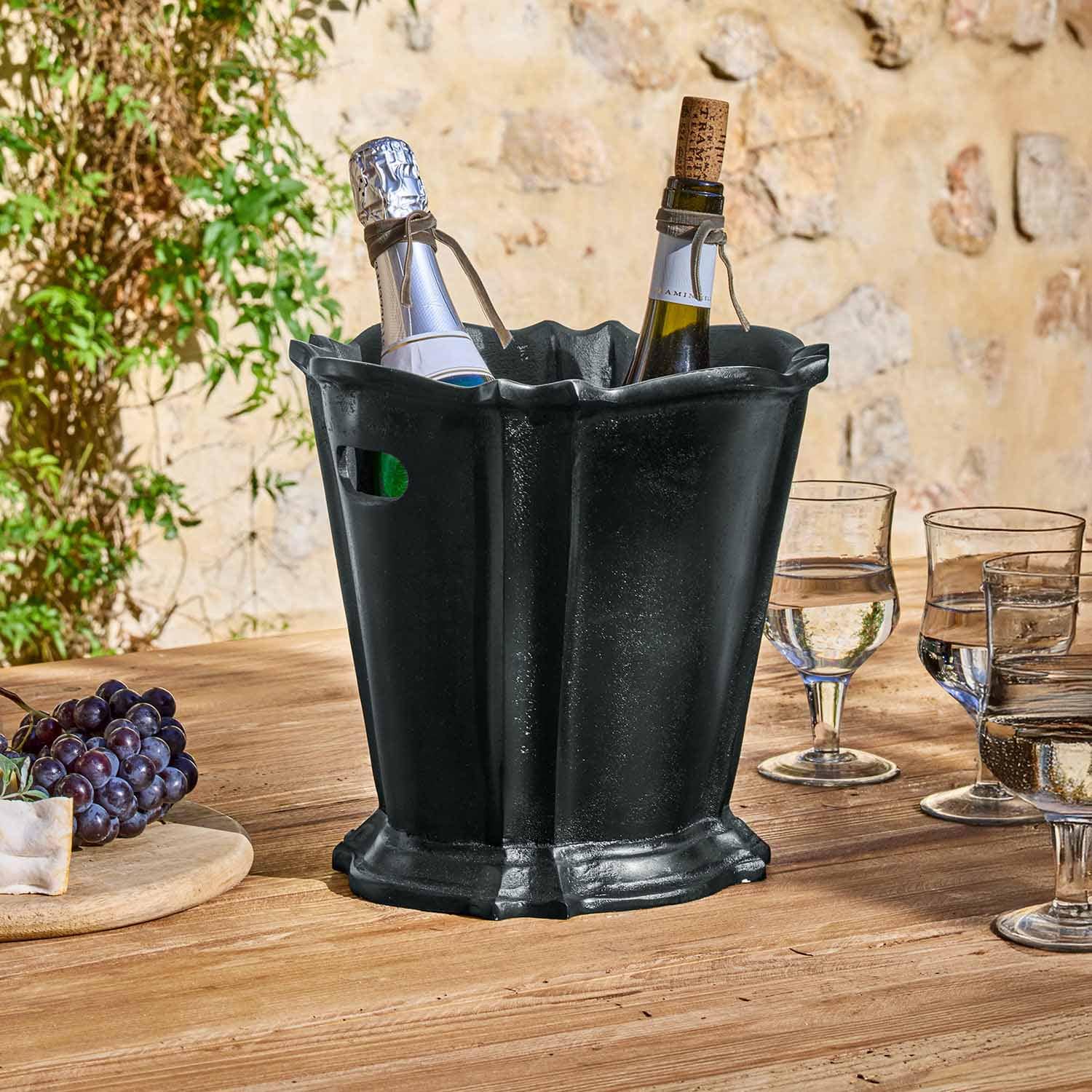 Schwarzer Eiswürfelbehälter aus Kunststoff mit zwei Flaschen und Gläsern auf Holztisch