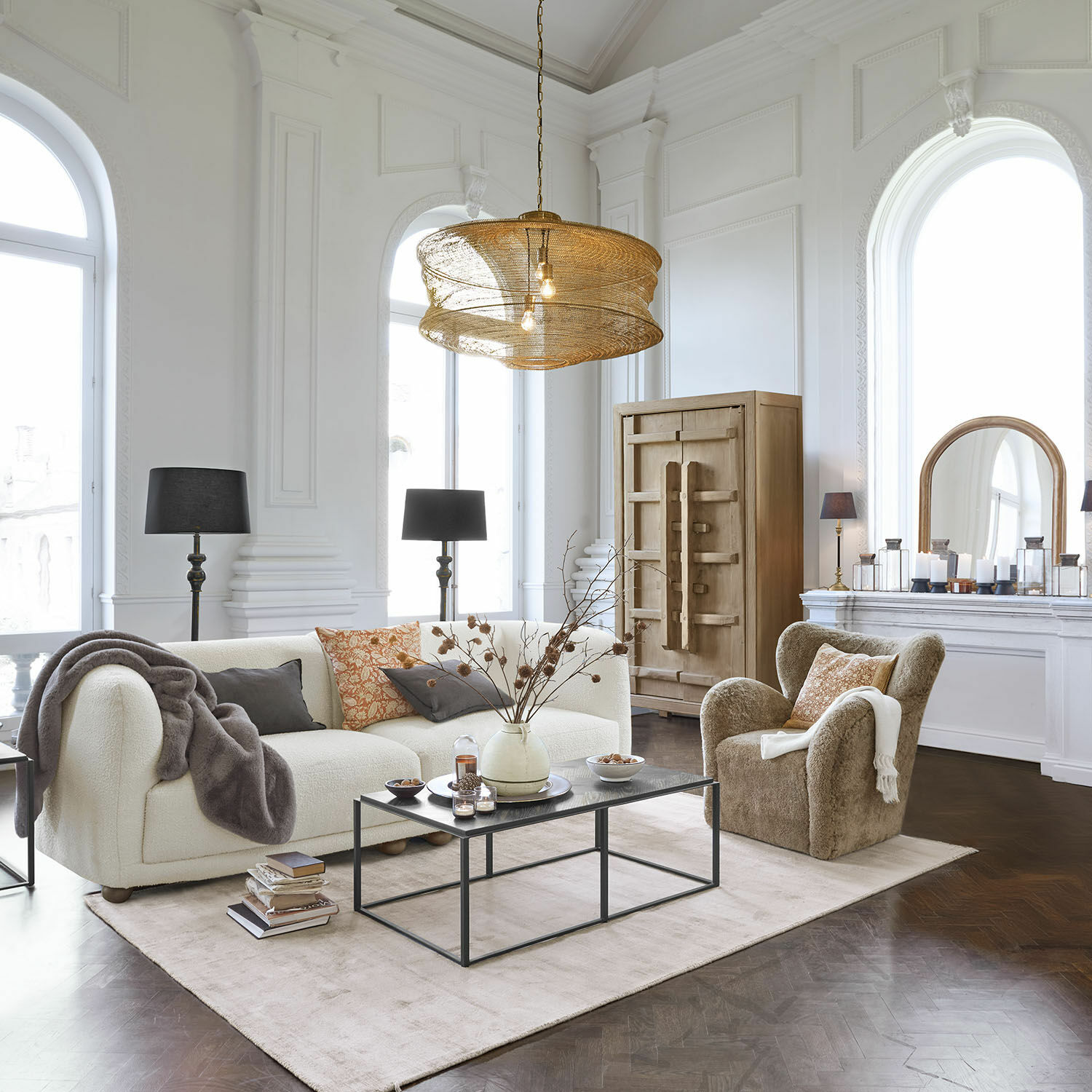 Gemütliches Wohnzimmer mit weißem Sofa und beigem Sessel aus weichem Material, schwarzem Couchtisch