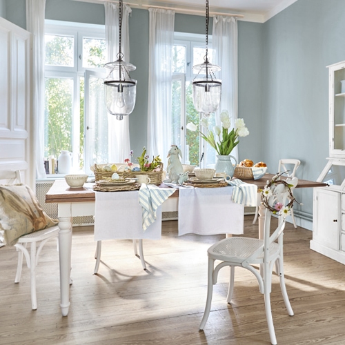 Rustikaler Essbereich mit weißem Holztisch und Stühlen, helle Pastell-Dekorationen