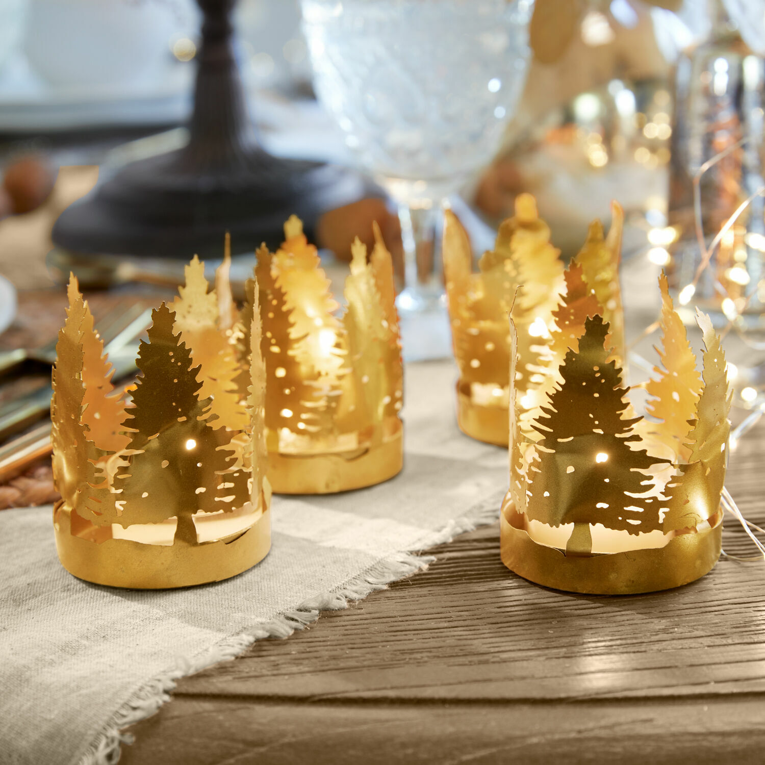 Teelichthalter 4er Set Ismerie Goldene Metall-Teelichthalter mit Tannenbaum-Motiv auf Holztisch, festliche Deko