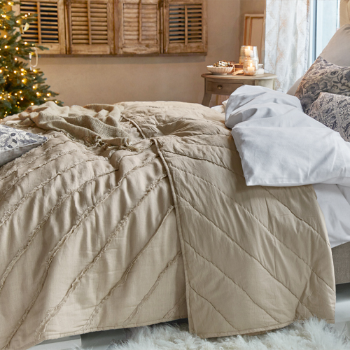 Beige Bettdecke aus weichem Material in gemütlichem Schlafzimmer mit Weihnachtsdekoration