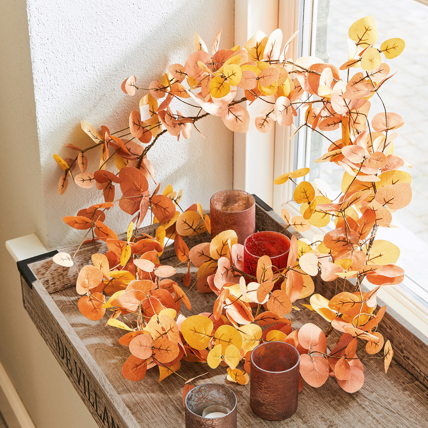 Herbstlicher Papierkranz mit orange-gelben Blättern auf dekorativem Holztablett arrangiert