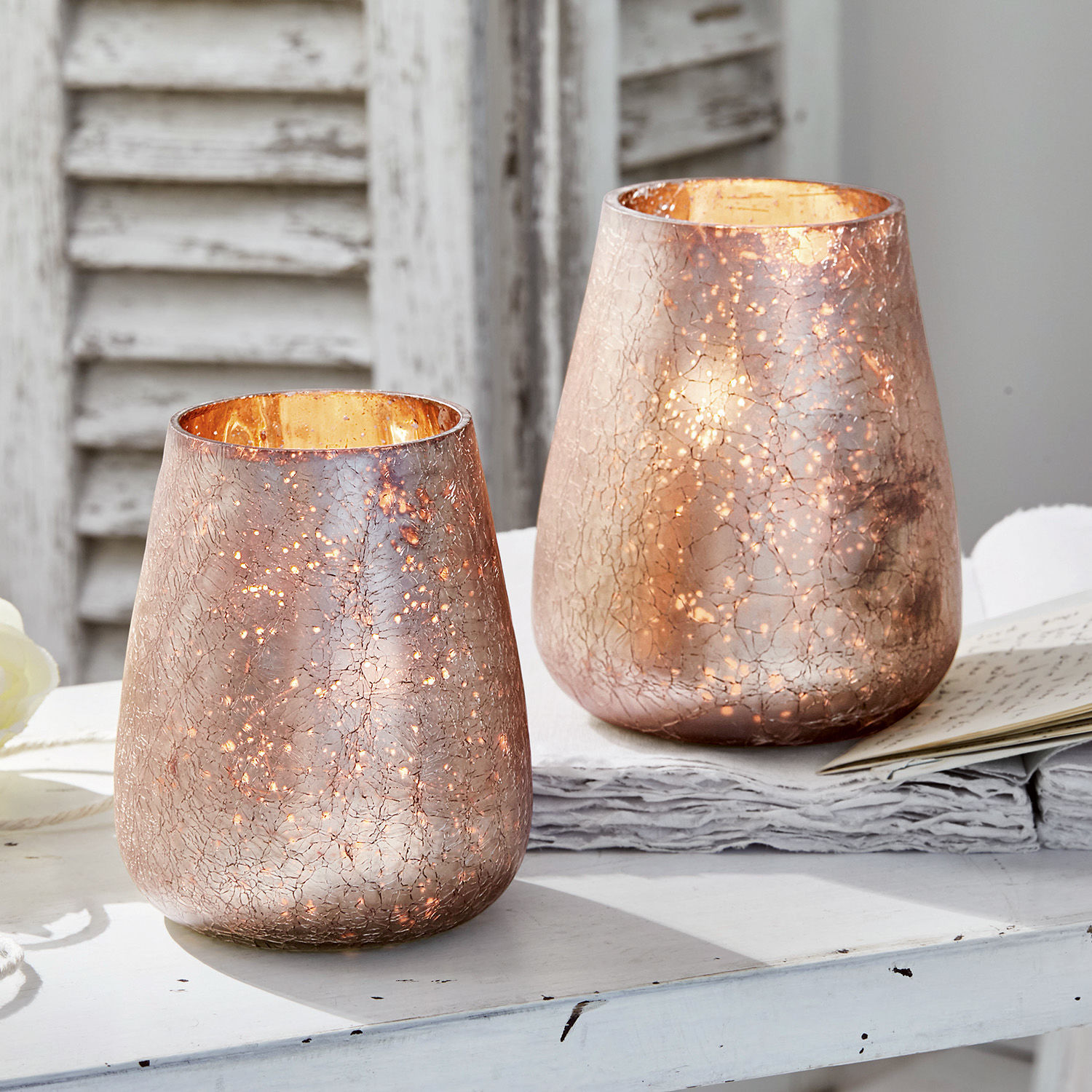 Windlicht 2er Set Chanut Zwei dekorative Windlichter aus kupferfarbenem Glas mit Riss-Effekt auf weißem Tisch