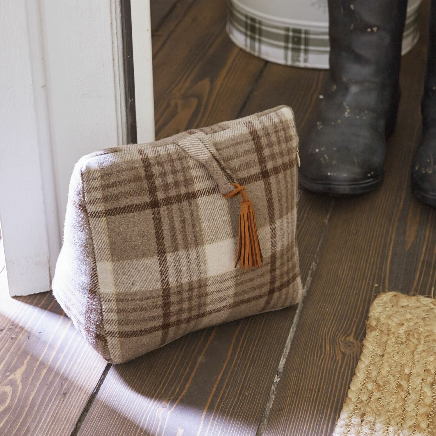 Türstopper Ersac Beige karierte Tasche aus weichem Stoff mit braunem Quastenanhänger auf Holzboden