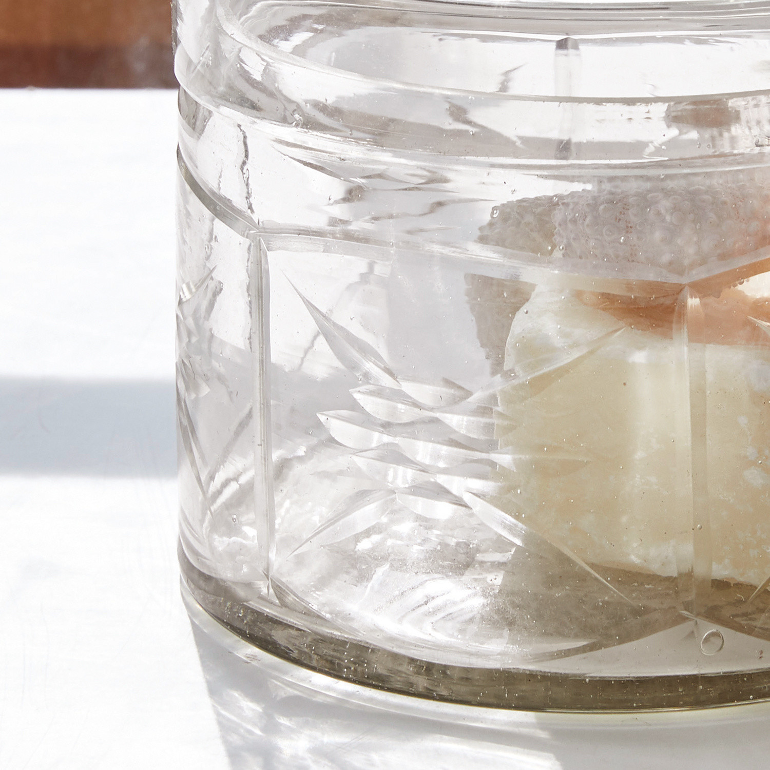 Transparenter Glasbehälter mit graviertem Muster und weißer Dekoration innen, dekoratives Glas