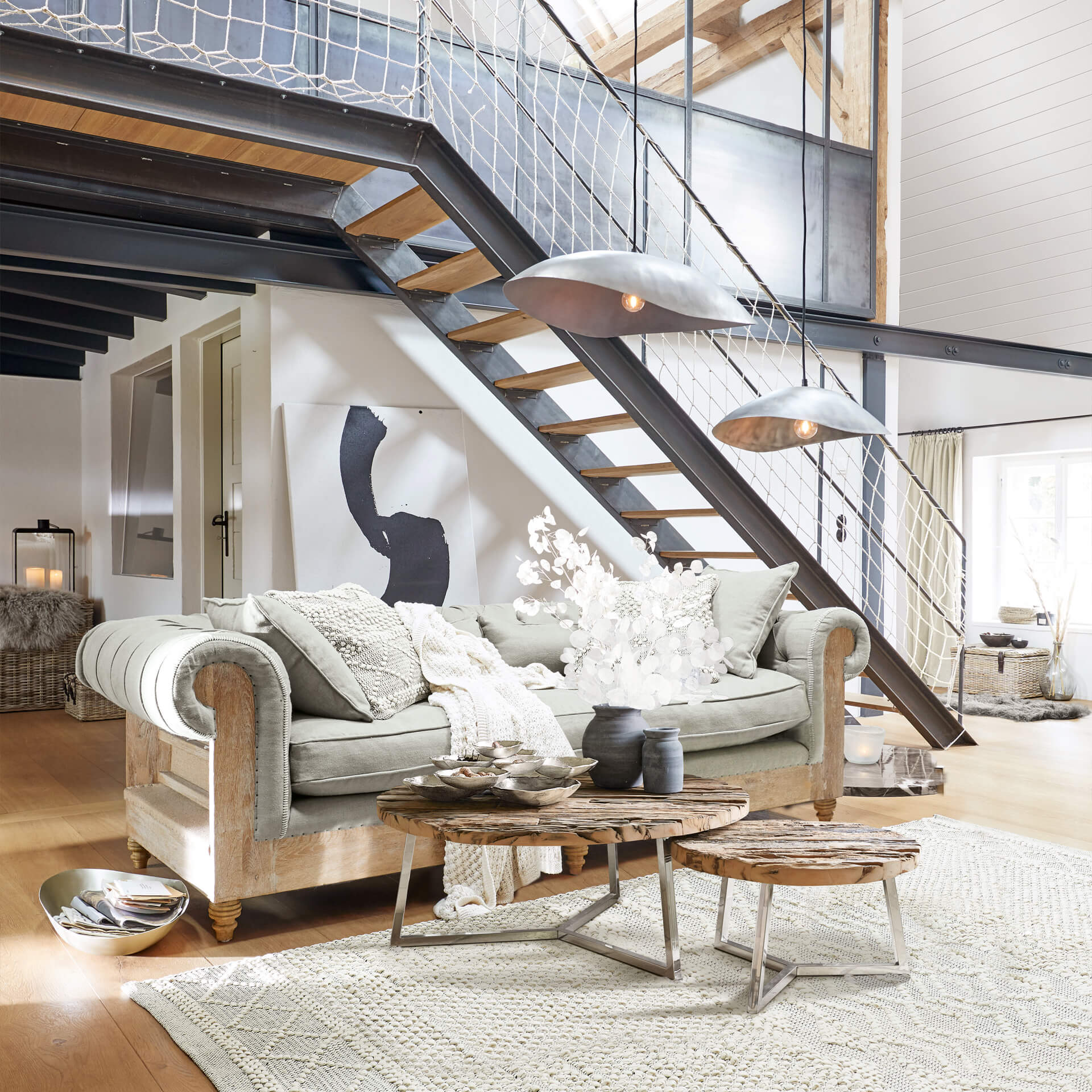 Wohnzimmer mit grauem Sofa aus Holzrahmen und zwei Couchtischen aus Holz und Metall auf hellem Teppich