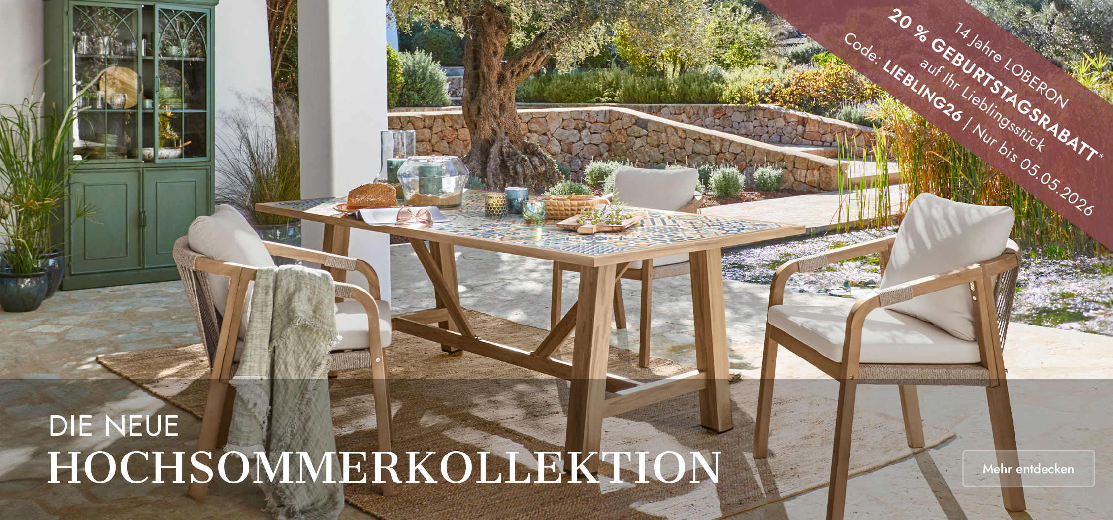 Gartenmöbel-Set mit Holztisch und Stühlen mit hellen Polstern auf sonniger Terrasse