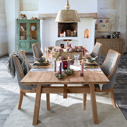Rustikaler Holzesstisch mit grauen Polsterstühlen und festlicher Dekoration im Landhausstil