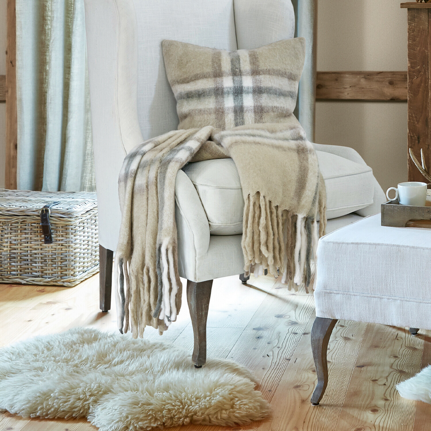 Plaid Klinas Beiger Polsterfessel und Hocker aus Stoff in gemütlichem Wohnzimmer mit Holzboden und Kamin