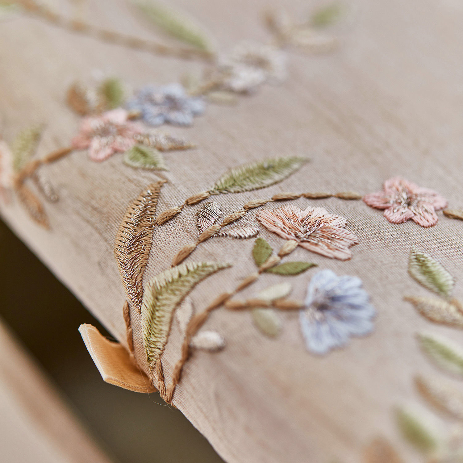 Beiger Stoff mit zarter Blumenstickerei in Pastellfarben, dekoratives Wohnaccessoire