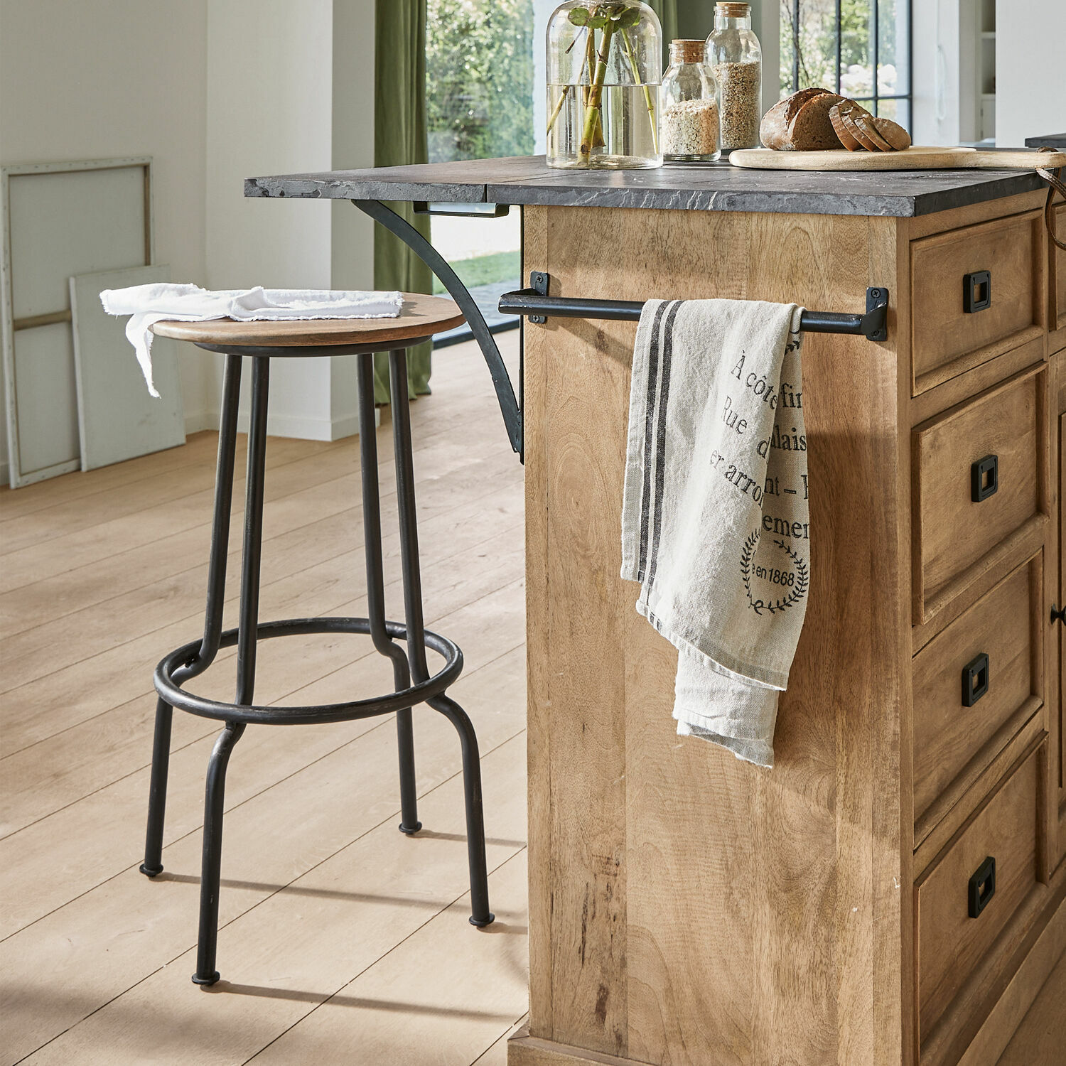 Kücheninsel aus Holz mit grauer Steinplatte und industriellem Metall-Barhocker in hellem Raum