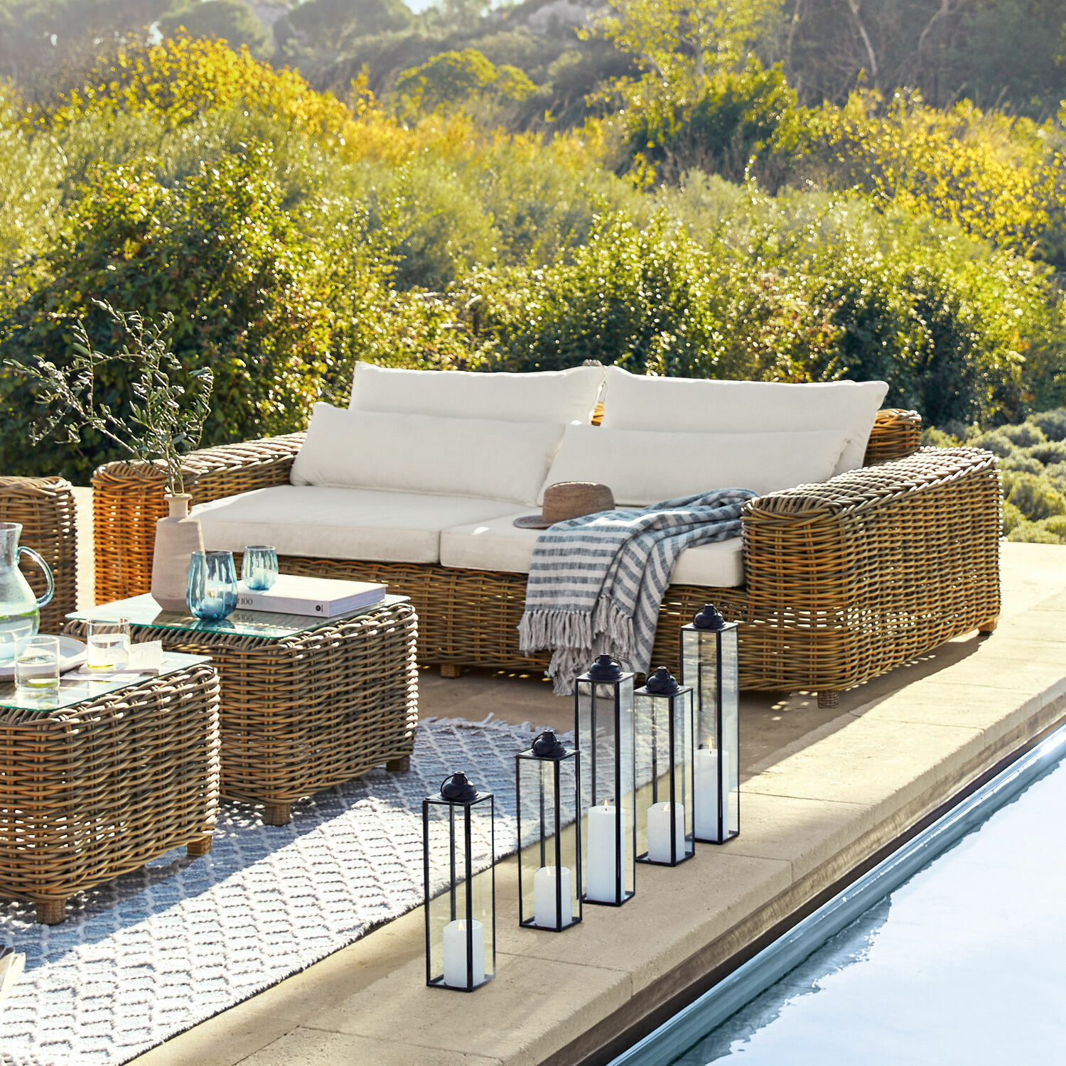Gartenmöbel-Set aus natürlichem Rattan mit cremefarbenen Kissen am Poolrand