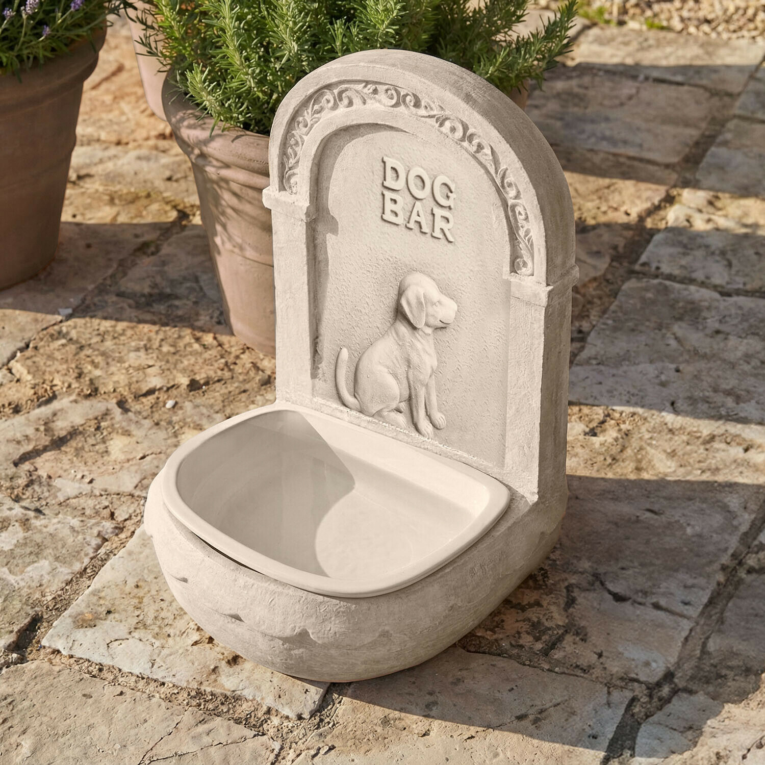 Grauer Hundetrinkbrunnen aus Stein mit Hundemotiv und Schriftzug DOG BAR außen