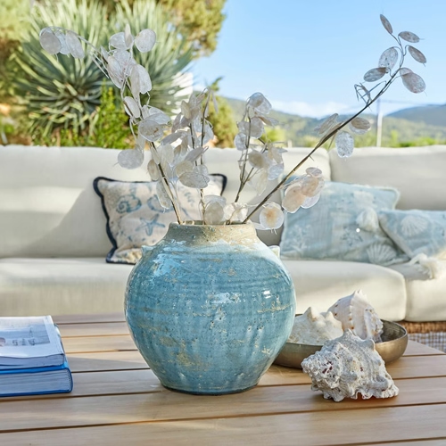 Blauer Keramikvase auf Holztisch mit getrockneten Pflanzen und Muscheln, stilvolle Wohnraumdekoration