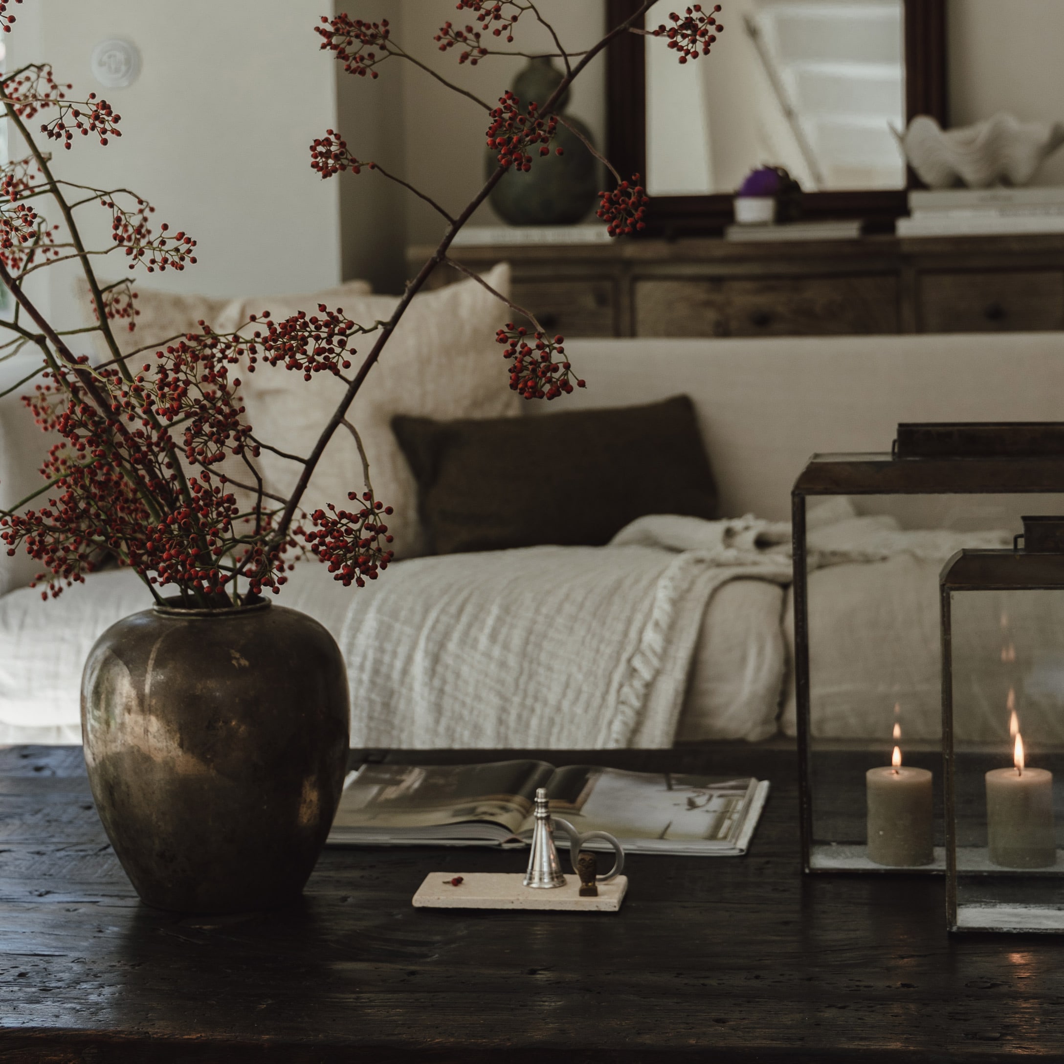 Dekorativer Vase mit roten Zweigen auf dunklem Holztisch in gemütlichem Wohnzimmer