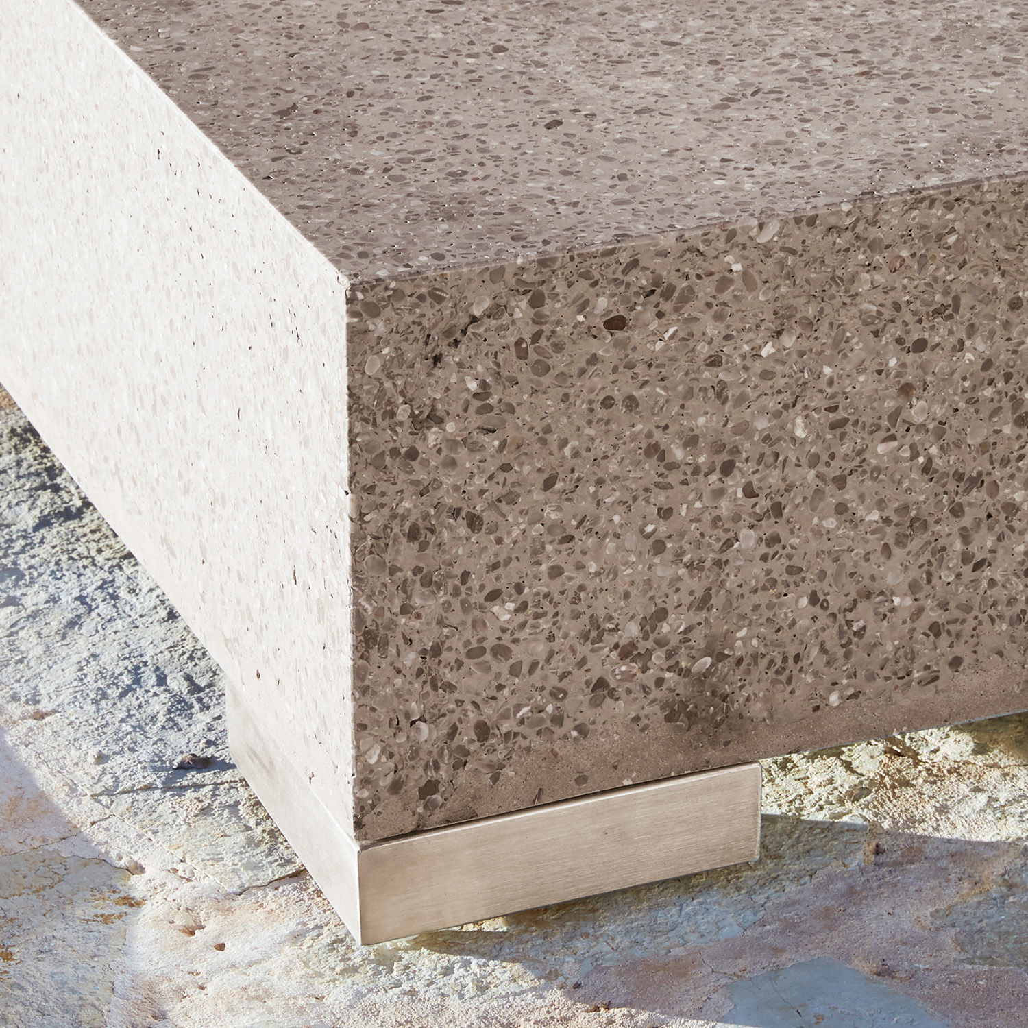 Eckdetail aus grauem Beton mit Metallfuß auf steinernem Boden, moderner Stil