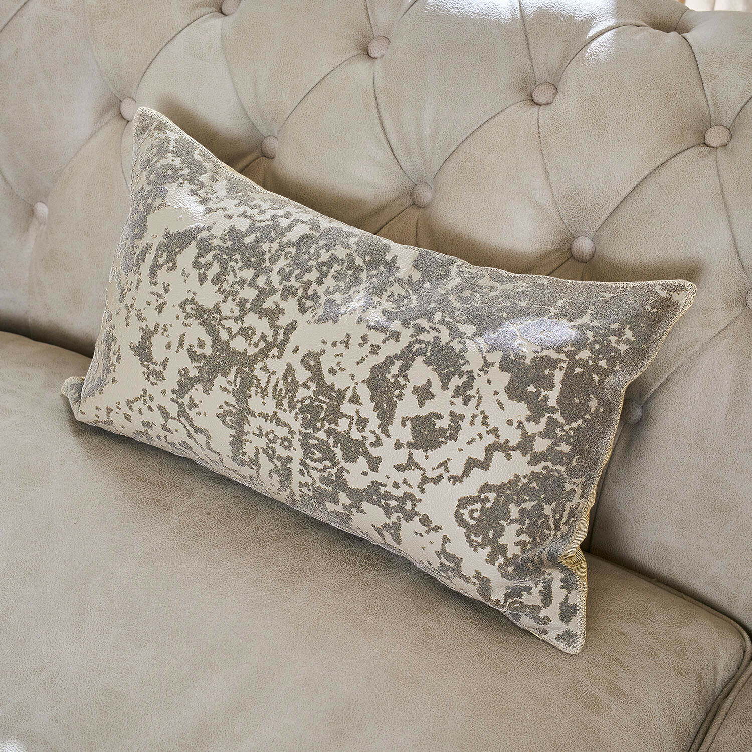 Rechteckiges Dekokissen mit grauem Muster auf hellbeigem, gepolstertem Sofa