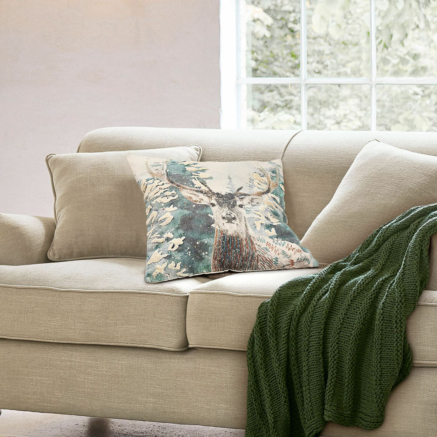 Kissenhülle Elvaris Beiges Sofa mit Hirschmotiv-Kissen und grünem Strickplaid in gemütlichem Wohnzimmer