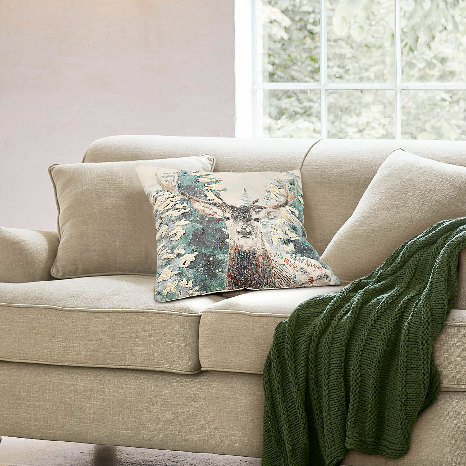 Kissenhülle Elvaris Beiges Sofa mit Hirschmotiv-Kissen und grünem Strickplaid in gemütlichem Wohnzimmer