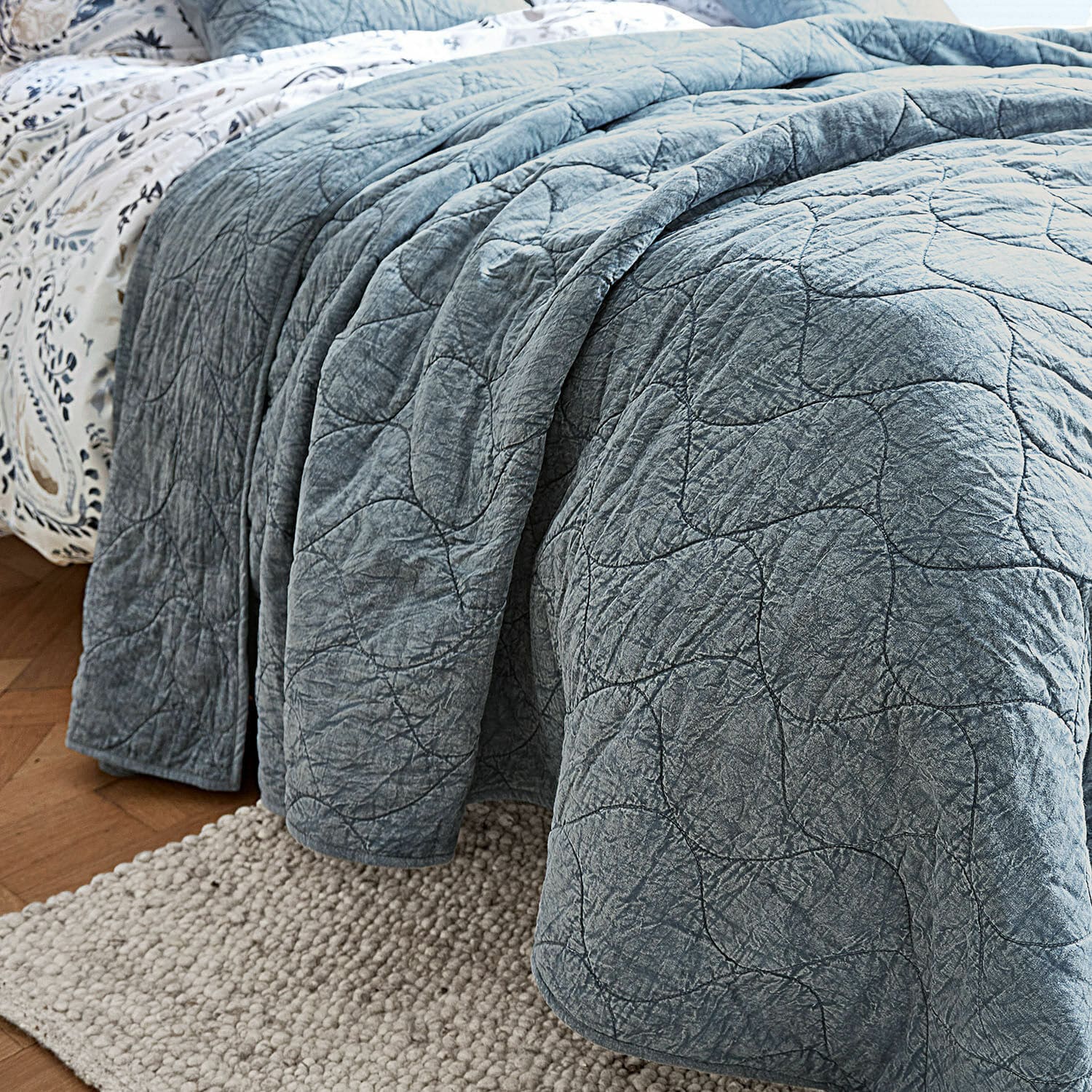 Blaues, gesteppte Decke aus weichem Material auf Bett, dekorativer und gemütlicher Wohntextil
