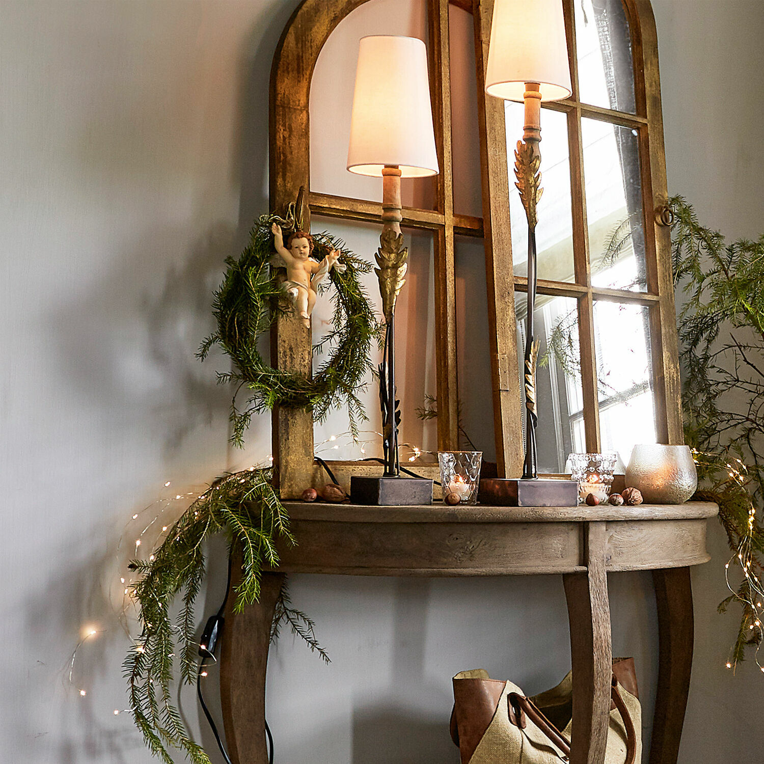 Holztisch mit Spiegel, Lampen und Weihnachtsdekoration mit grünem Kranz und Engel-Figur