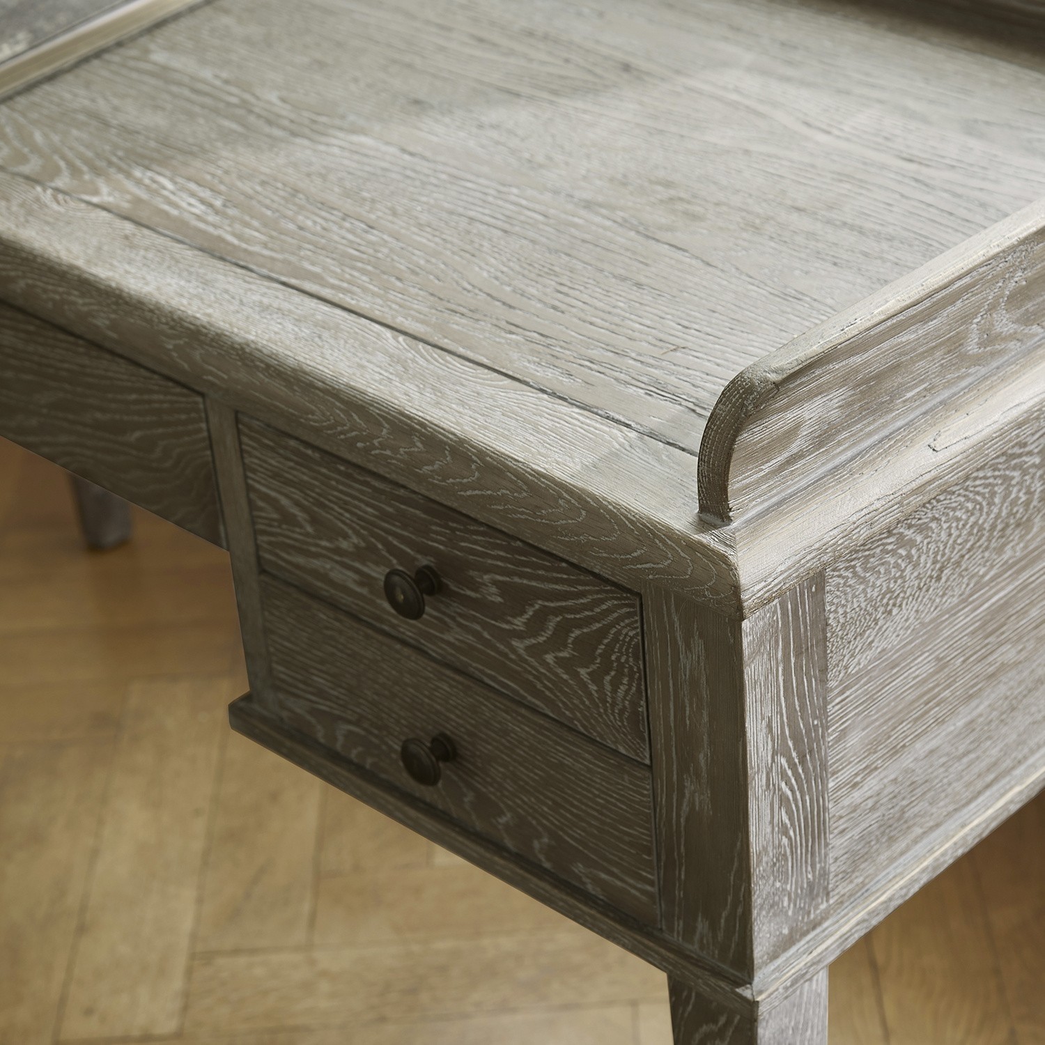 Schreibtisch aus grauem Holz mit sichtbarer Maserung und zwei Schubladen auf Holzbeinen