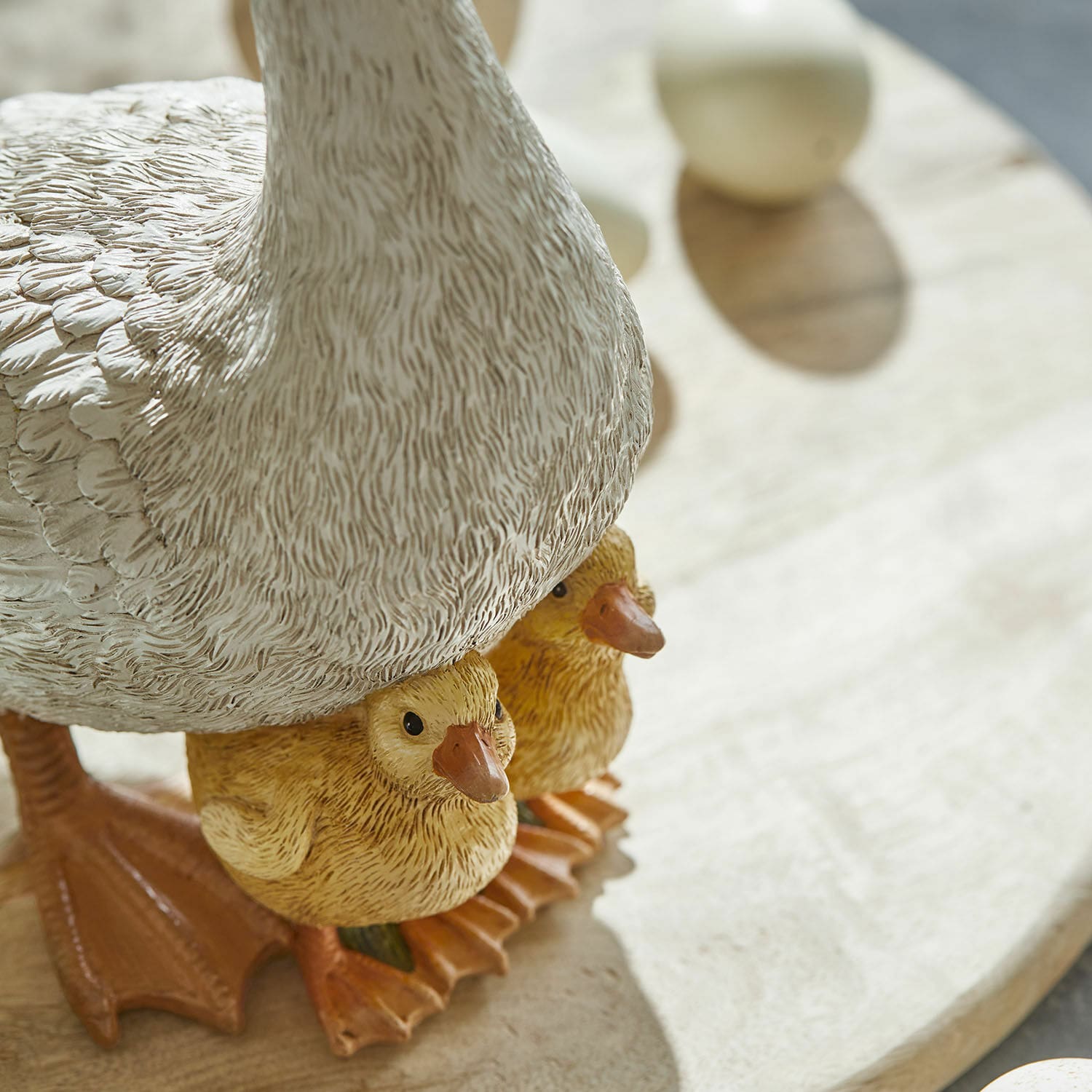 Dekofigur Ente mit zwei gelben Küken auf Holzuntergrund, detailreiche Wohnaccessoire
