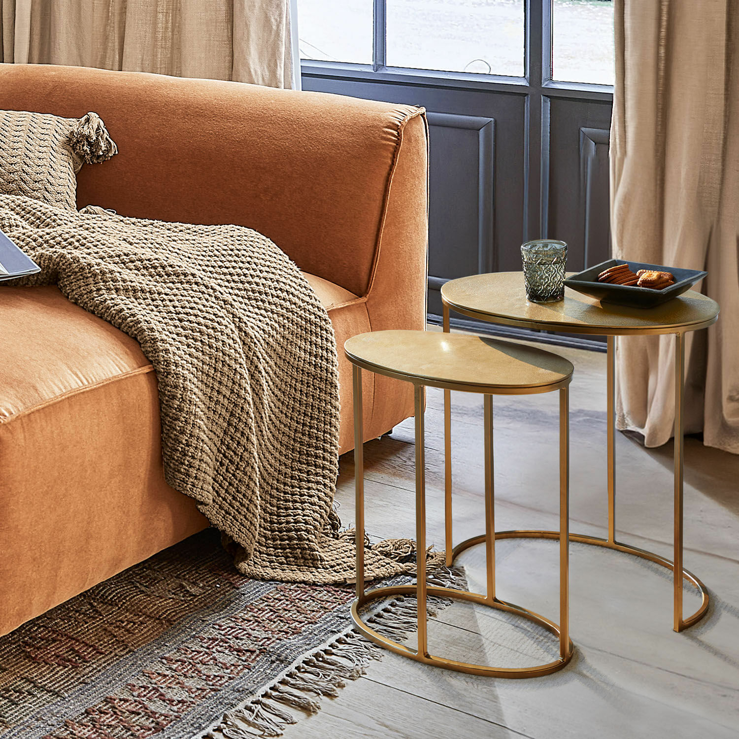 Zweier-Set goldene Beistelltische aus Metall neben orangefarbenem Sofa mit beigem Plaid