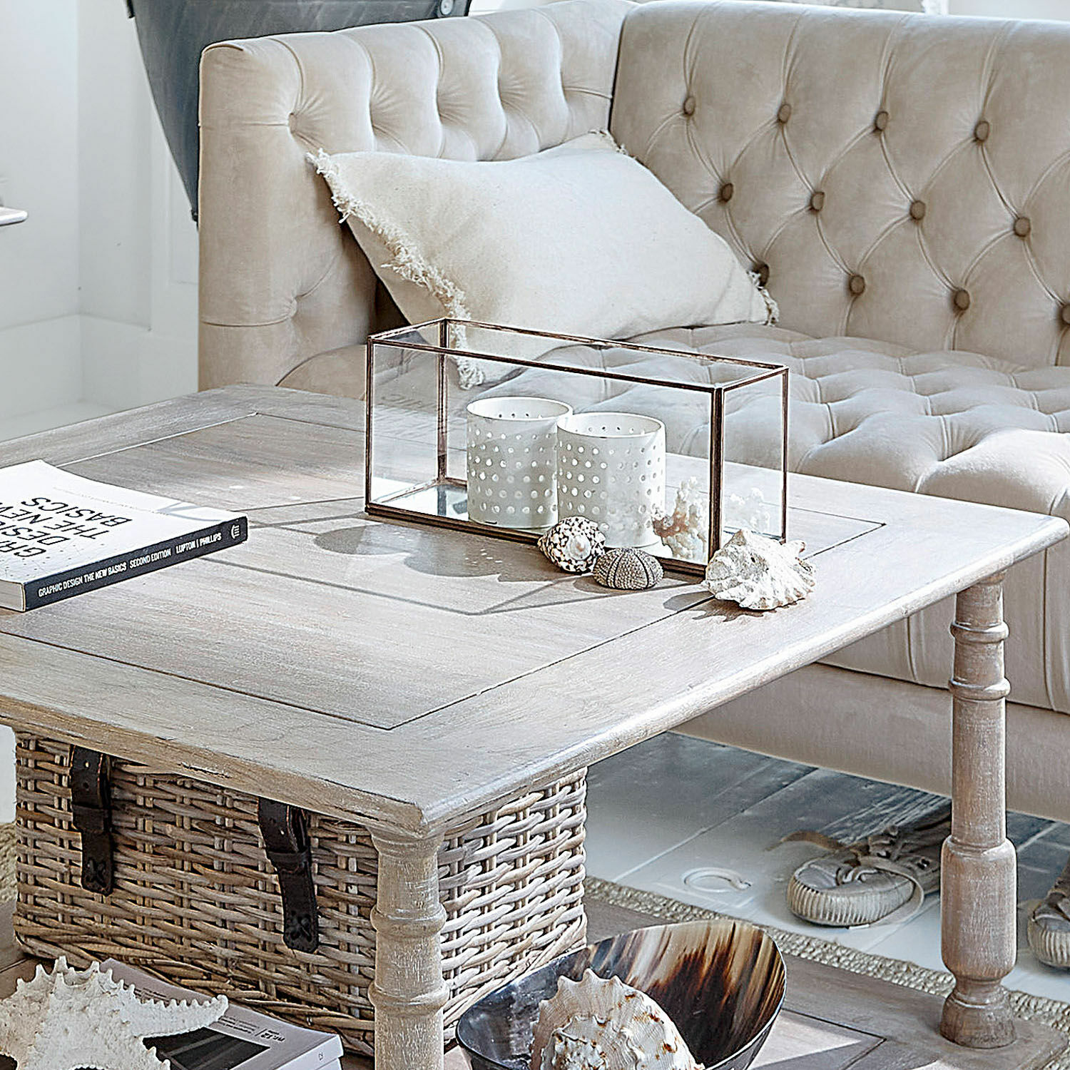 Heller Holzcouchtisch mit Korb und Dekoration vor beigem, gesteppter Sofa im Wohnzimmer