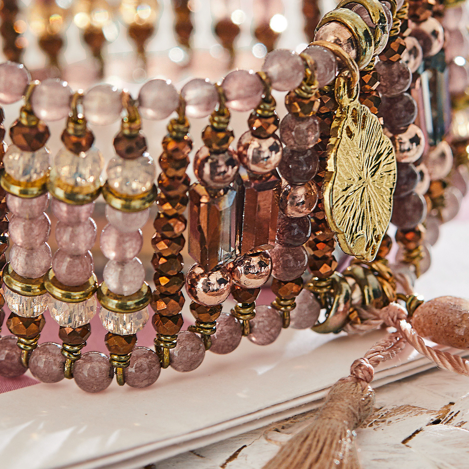 Armband aus rosa und braunen Perlen mit goldenem Metallanhänger und Quaste
