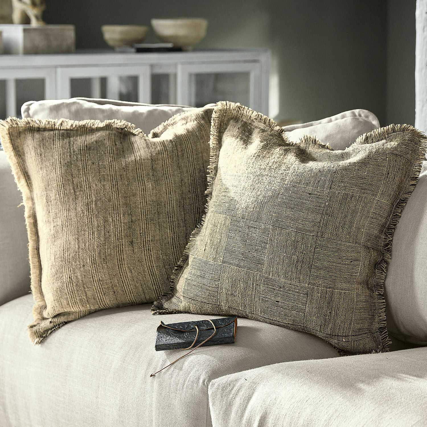 Kissenhülle 2er Set Amur Zwei beige dekorative Kissen mit Fransen auf hellgrauem Sofa in modernem Wohnzimmer