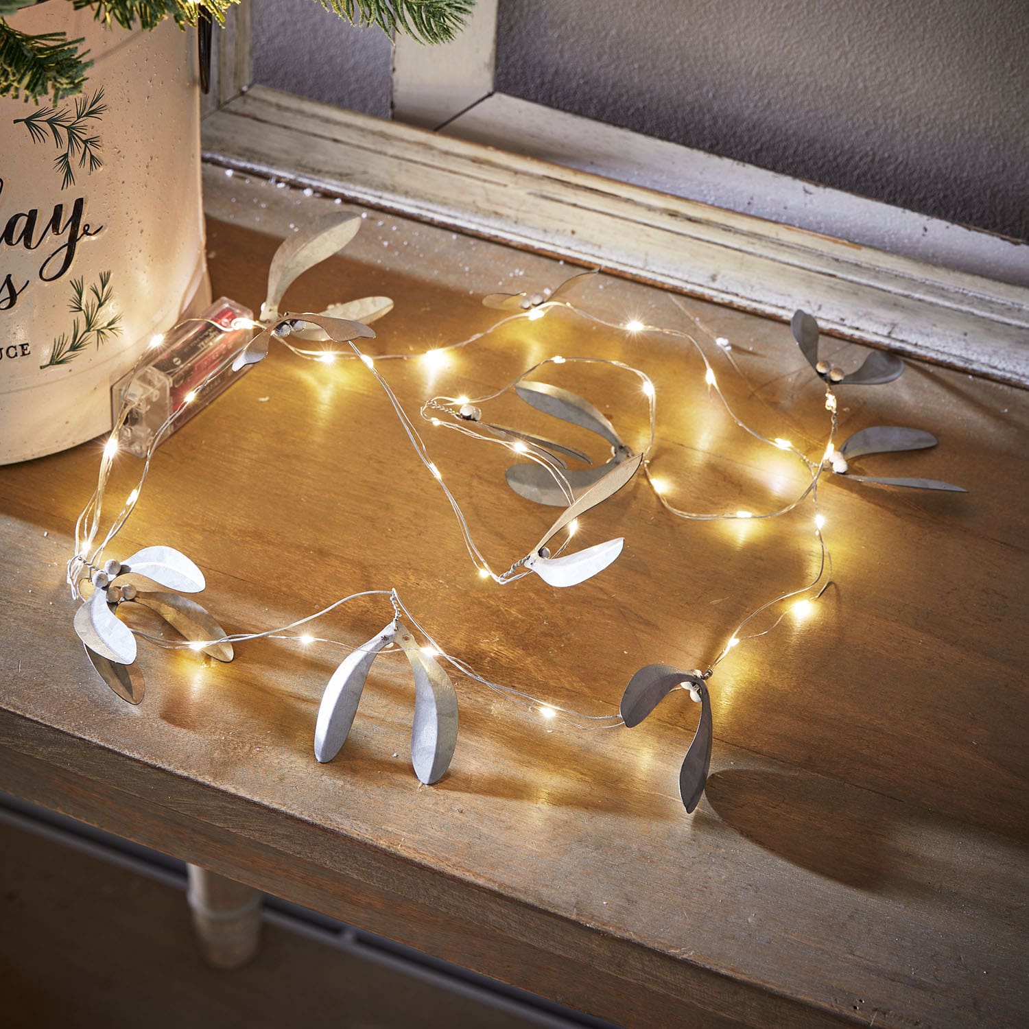 Feine Lichterkette mit silbernen Metallblättern auf Holztisch, stimmungsvolle Weihnachtsdekoration