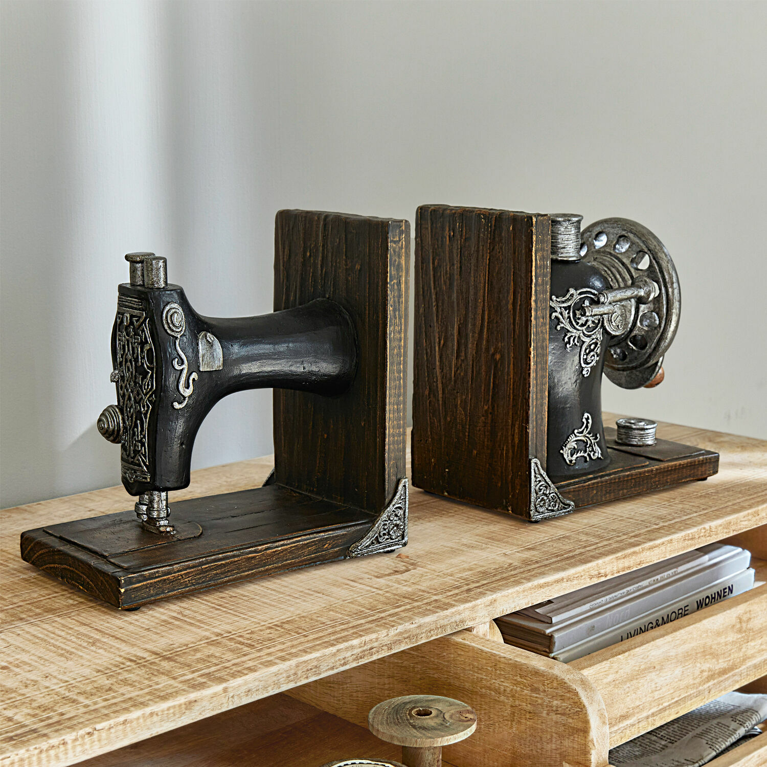 Holzbuchstützen in Form einer schwarzen Nähmaschine mit Metallverzierungen auf Holztisch