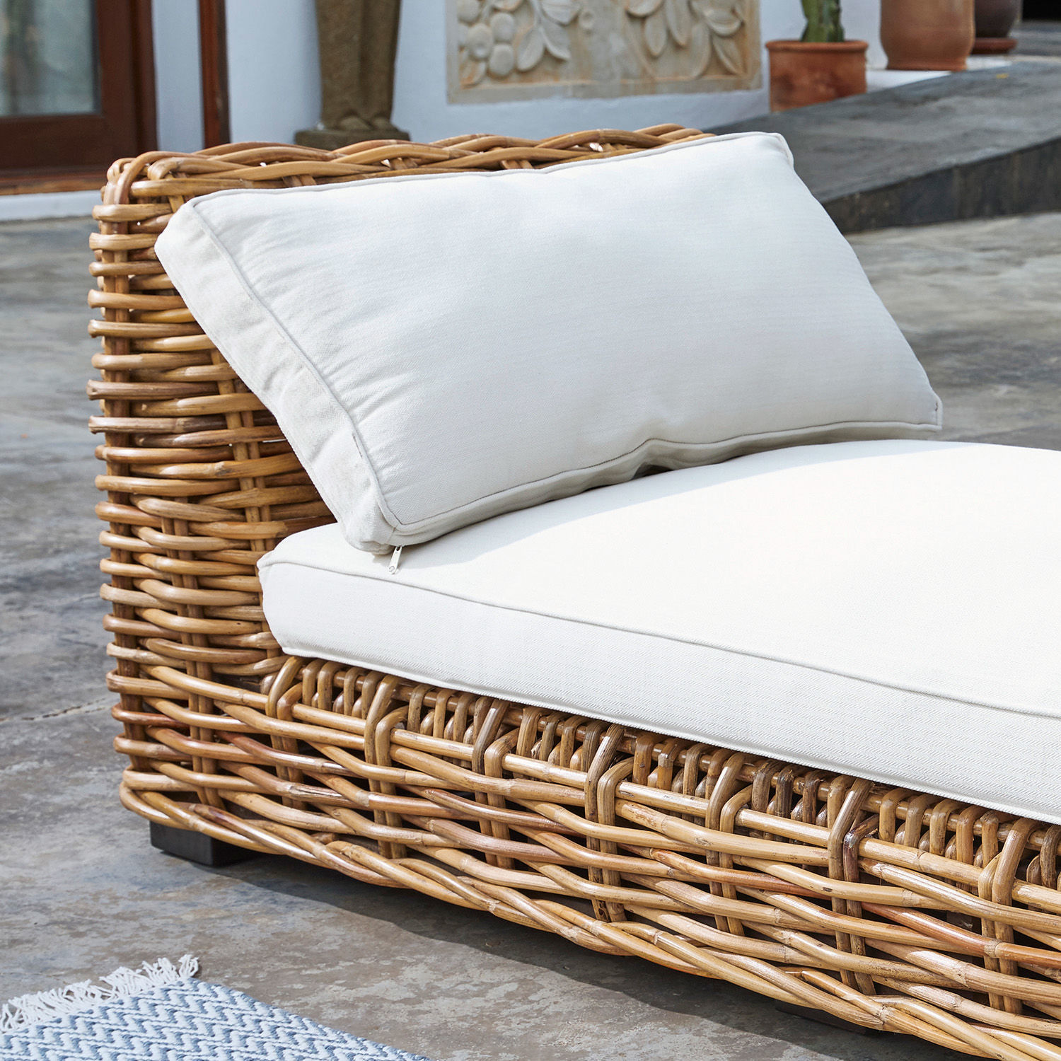 Rattansofa mit cremefarbenen Kissen, Gartenmöbel aus Naturmaterial für entspannte Stunden