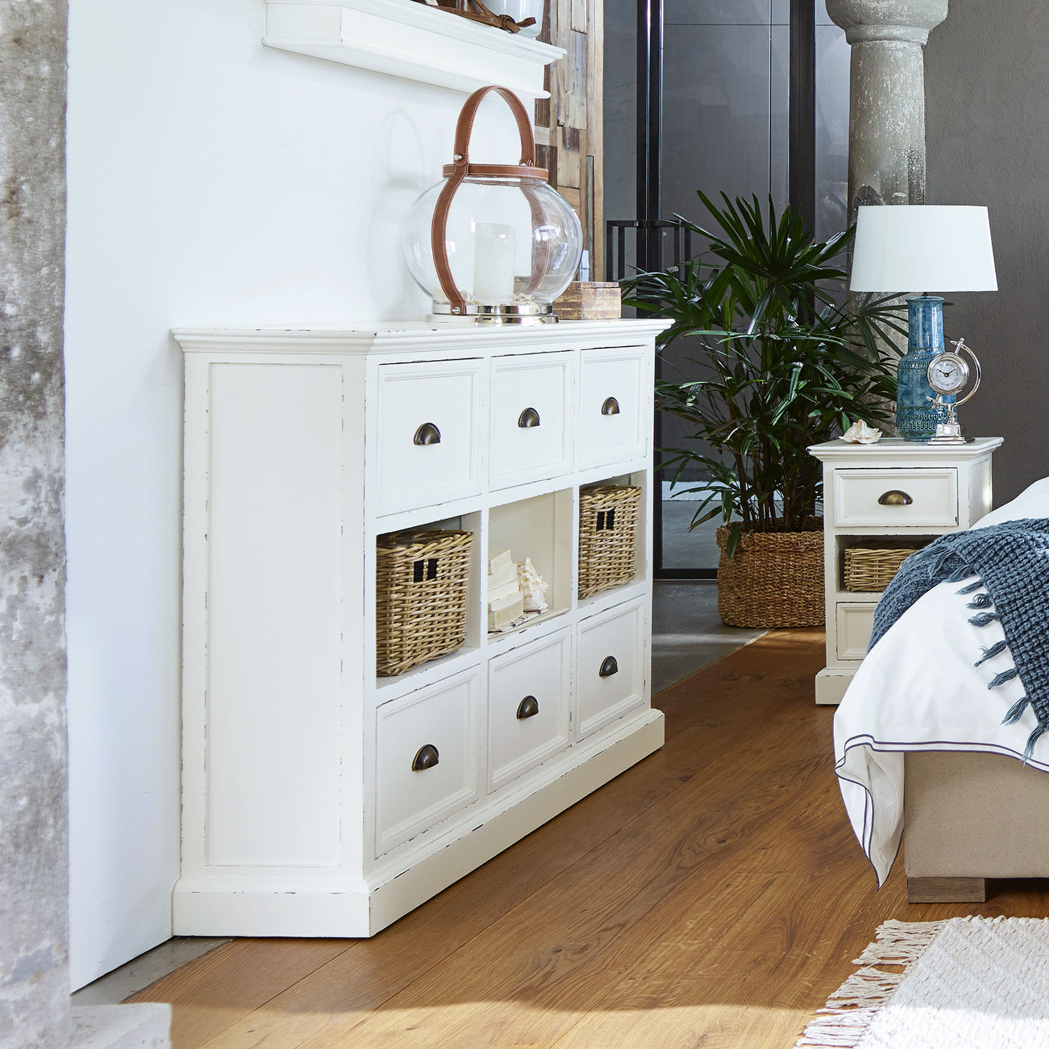 Weiße Holzkommode mit Schubladen und Rattankörben in modernem Schlafzimmer