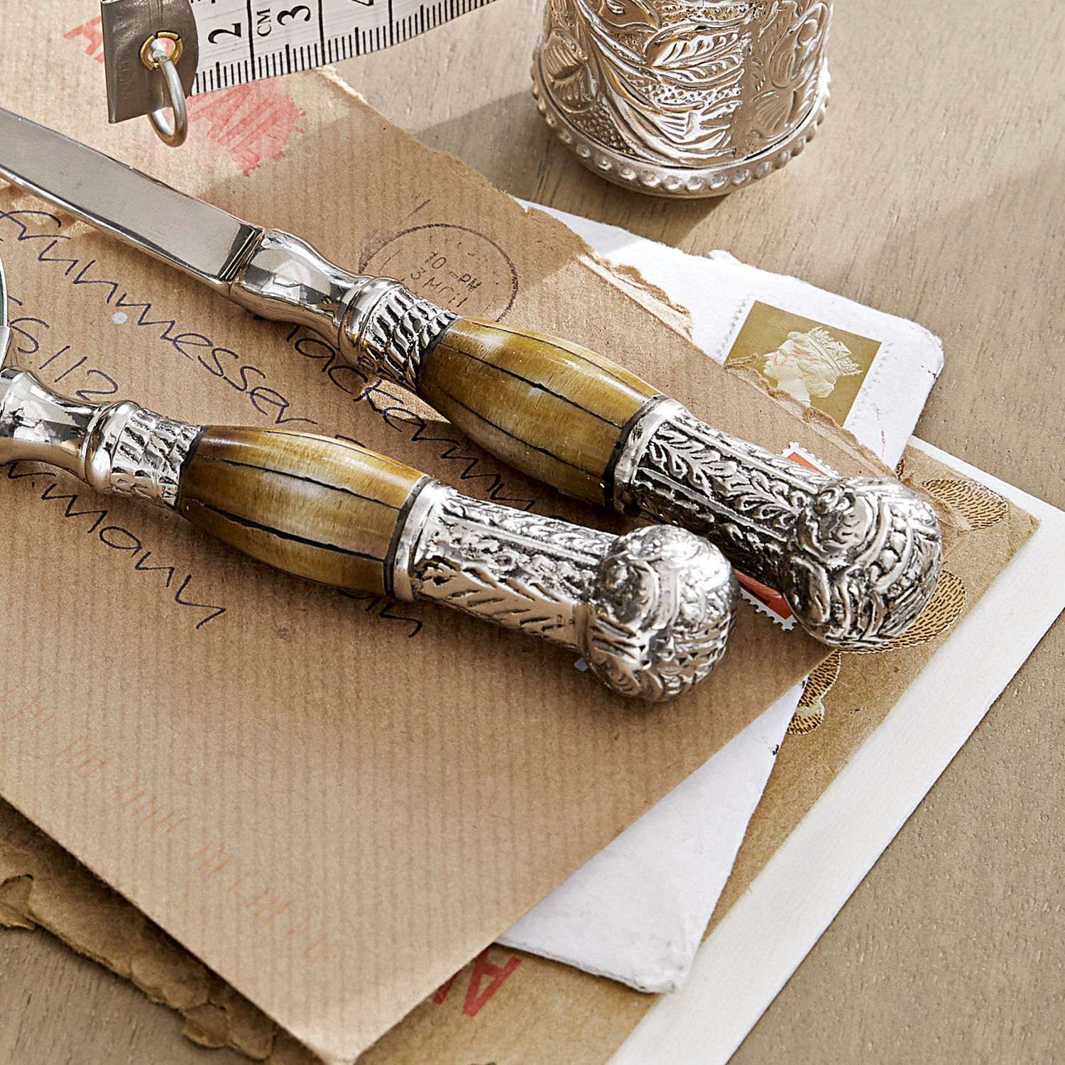 Set Buttermesser mit Holzgriff und verziertem Metall auf Briefumschlägen liegend